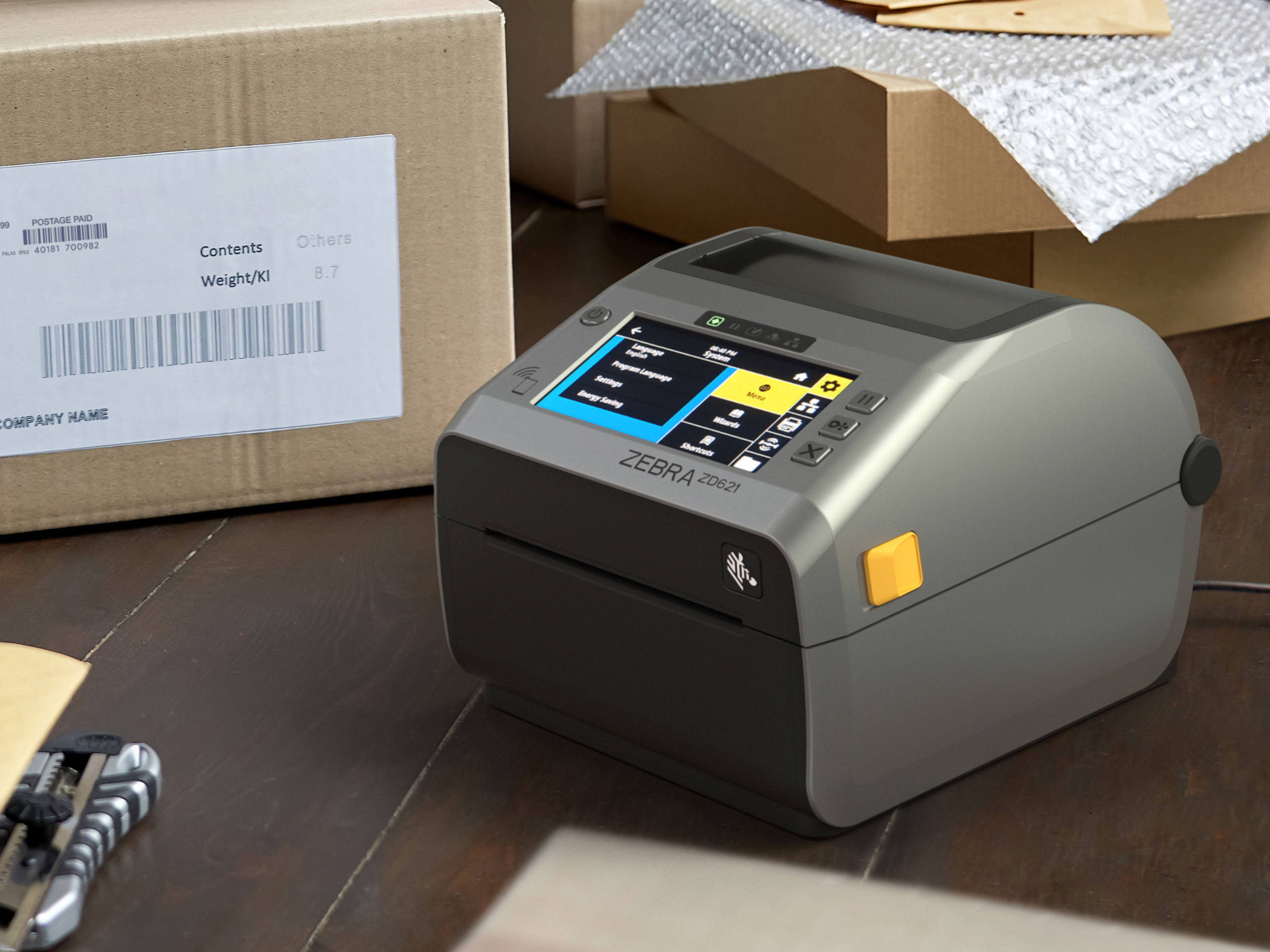 Front left view of a Zebra ZD621 desktop printer in a packing environment, showcasing its application and functionality including label printing.